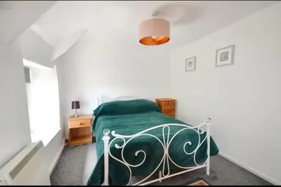 a bedroom with a bed with a green blanket at Harvest Cottage in Constantine