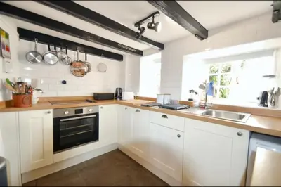 a kitchen with white cabinets and a sink and a window at Harvest Cottage in Constantine