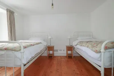 two white beds in a room with wooden floors at 84 Fore Street in Port Isaac