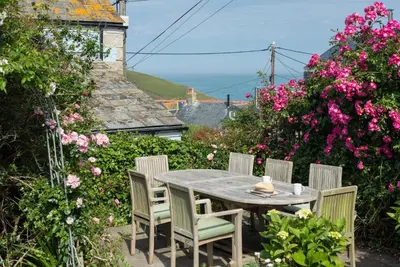 a table and chairs in a garden with flowers at 84 Fore Street in Port Isaac