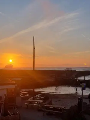 a sunset on the beach with the sun setting at Sandy Paws in Portreath