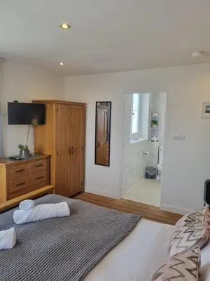 a bedroom with a bed and a dresser and a bathroom at Sandy Paws in Portreath