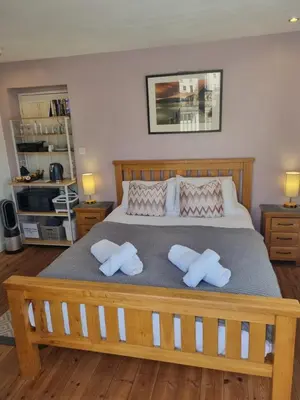 a bedroom with a large bed with two pillows at Sandy Paws in Portreath