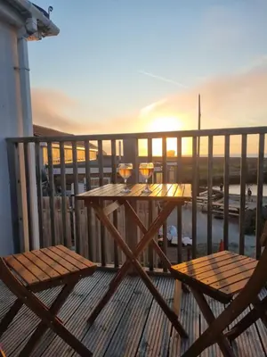 a table with two glasses of wine on a balcony at Sandy Paws in Portreath