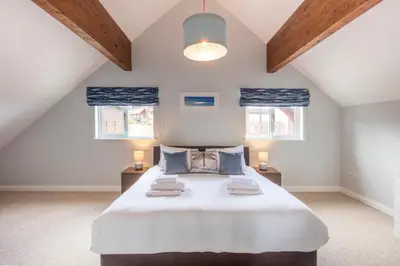a bedroom with a large bed and two windows at Sunrise in Saint Columb Major