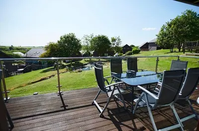 a table and chairs on a deck with a view of a field at Sunrise in Saint Columb Major