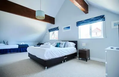 a bedroom with two beds and blue walls at Sunrise in Saint Columb Major