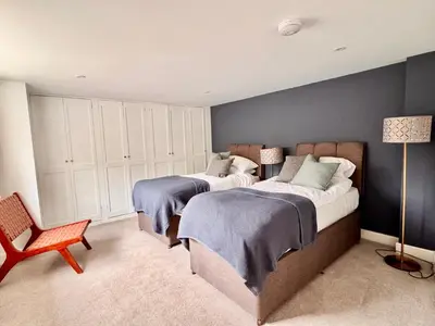 a bedroom with two beds and a chair at Penheyl, Tregonce near Padstow and Sea in St. Issey