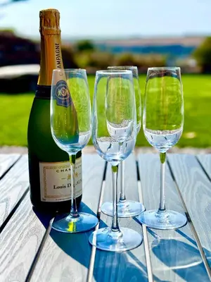 three wine glasses sitting on a table next to a bottle at Penheyl, Tregonce near Padstow and Sea in St. Issey