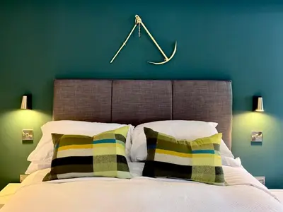a bed with two pillows and a clock on the wall at Penheyl, Tregonce near Padstow and Sea in St. Issey