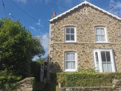 a brick house with white windows and a hedge at Single room, close to beaches and Eden Project in Tywardreath