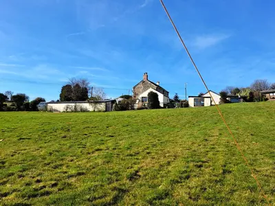 a green field with a house in the background at Bell Tent 2 in St Austell