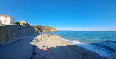 a beach with a retaining wall and the ocean at Bell Tent 2 in St Austell