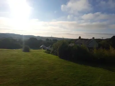 a grassy field with houses in the distance at Bell Tent 2 in St Austell
