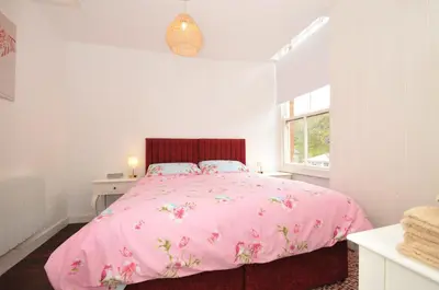 a bedroom with a pink bed and a window at Stargazy in Tintagel