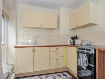 a kitchen with white cabinets and a sink and a stove at Stargazy in Tintagel