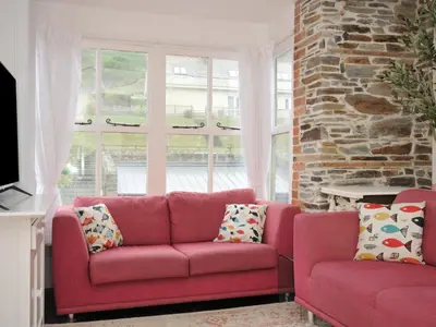 a living room with a red couch and a brick wall at Stargazy in Tintagel