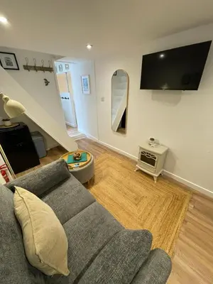 a living room with a couch and a tv at Bagnalls Studio, a newly renovated studio in a traditional fisherman's cottage in St Ives