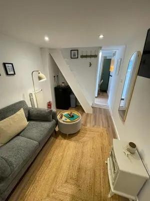 a living room with a couch and a stair case at Bagnalls Studio, a newly renovated studio in a traditional fisherman's cottage in St Ives