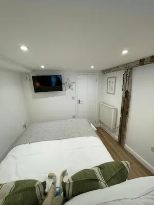 a bedroom with a bed and a tv on the wall at Bagnalls Studio, a newly renovated studio in a traditional fisherman's cottage in St Ives