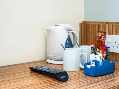 a remote control sitting next to cups and a coffee maker at The Feather's Hotel Newquay in Newquay