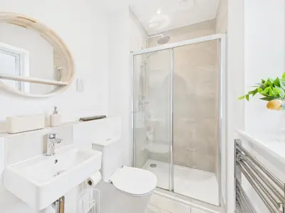 a white bathroom with a shower and a toilet and sink at Beachside Retreat by Signature Stays - Modern Coastal Home in Hayle