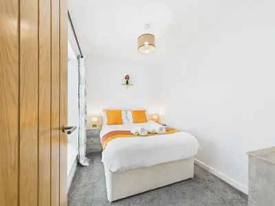 a bedroom with a bed with white sheets and orange pillows at Beachside Retreat by Signature Stays - Modern Coastal Home in Hayle