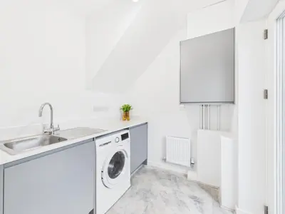a white kitchen with a washer and dryer at Beachside Retreat by Signature Stays - Modern Coastal Home in Hayle