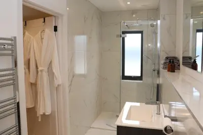 a white bathroom with a sink and a shower at The Hidden Sanctuary in Stithians