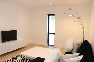 a white living room with a couch and a tv at The Hidden Sanctuary in Stithians