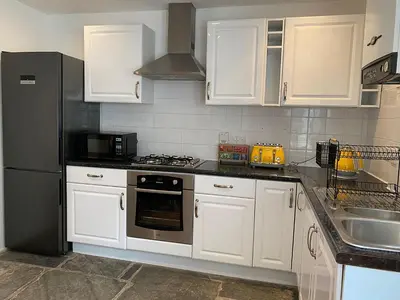 a kitchen with white cabinets and a stainless steel refrigerator at Central, 10min walk to beach with off-road parking in Falmouth