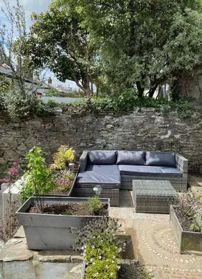 a couch sitting in the middle of a garden at Central, 10min walk to beach with off-road parking in Falmouth