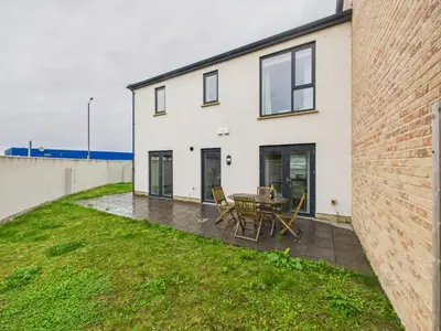 a white house with a patio and a table at No4 Harveys Yard By Signature Stays - Luxury Stay - Beach - Parking in Hayle