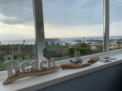 a window sill with a view of the ocean at Bungalow with stunning views over Widemouth Bay in Widemouth Bay