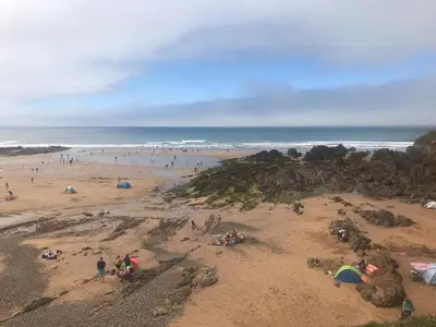 a group of people on a beach near the ocean at Bungalow with stunning views over Widemouth Bay in Widemouth Bay