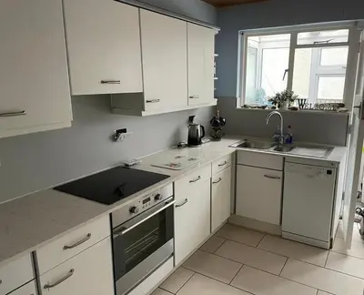 a kitchen with white cabinets and a sink and a window at Bungalow with stunning views over Widemouth Bay in Widemouth Bay