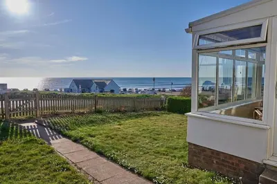 a house with a window looking out at the beach at Bungalow with stunning views over Widemouth Bay in Widemouth Bay