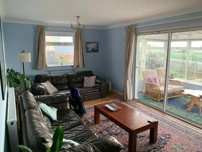 a living room with a couch and a table at Bungalow with stunning views over Widemouth Bay in Widemouth Bay