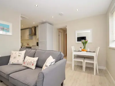 a living room with a gray couch and a table at Evelyn in Looe