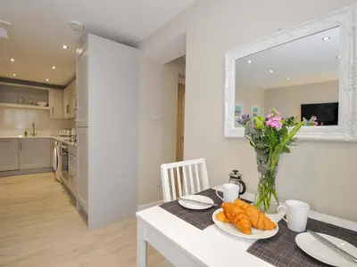 a kitchen and dining room with a table with a vase of flowers at Evelyn in Looe