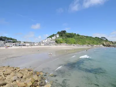 a beach with a bunch of people in the water at Evelyn in Looe