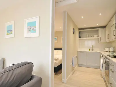 a room with a kitchen and a living room at Evelyn in Looe