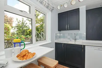 a kitchen with black cabinets and a plate of bread at 2 Porthilly Cottages in Wadebridge