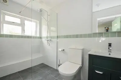 a bathroom with a toilet and a glass shower at 2 Porthilly Cottages in Wadebridge