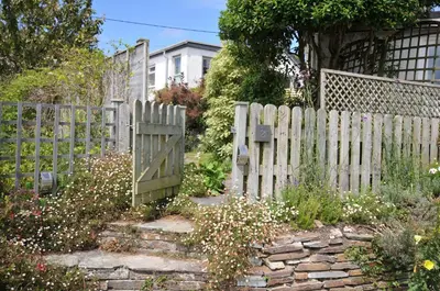 a wooden fence with a gate in a garden at 2 Porthilly Cottages in Wadebridge