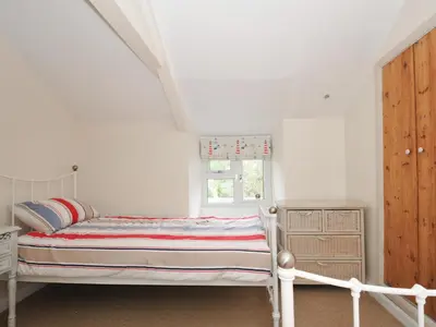 a white bedroom with a bed and a window at 2 Porthilly Cottages in Wadebridge
