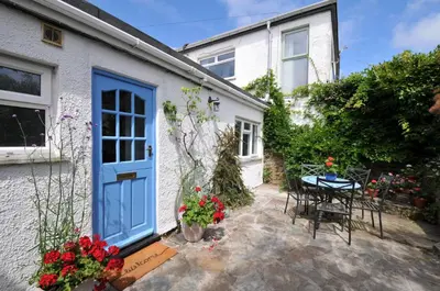 a house with a blue door and a table with flowers at 2 Porthilly Cottages in Wadebridge