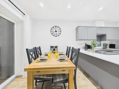 a kitchen with a wooden table and chairs in a kitchen at Harveys Yard by Signature Stays - Luxury home - Beach - Parking in Hayle