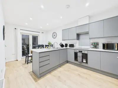 a kitchen with white cabinets and a dining room at Harveys Yard by Signature Stays - Luxury home - Beach - Parking in Hayle