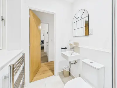 a white bathroom with a sink and a toilet at Harveys Yard by Signature Stays - Luxury home - Beach - Parking in Hayle